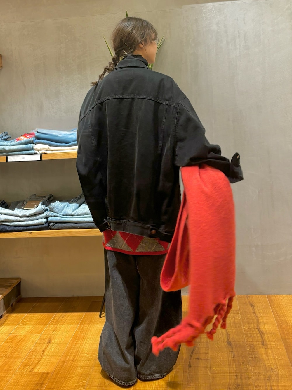 ブラック系のデニムジャケット、レッド系のニット/セーター、ブラック系のデニムパンツを着用したレディースの秋コーディネートの6枚目の写真