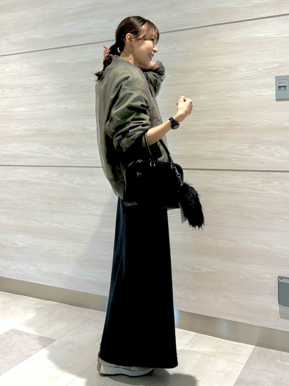 イエロー系のニット/セーター、グレー系のスカート、グリーン系のMA-1を着用したレディースの秋コーディネートの2枚目の写真