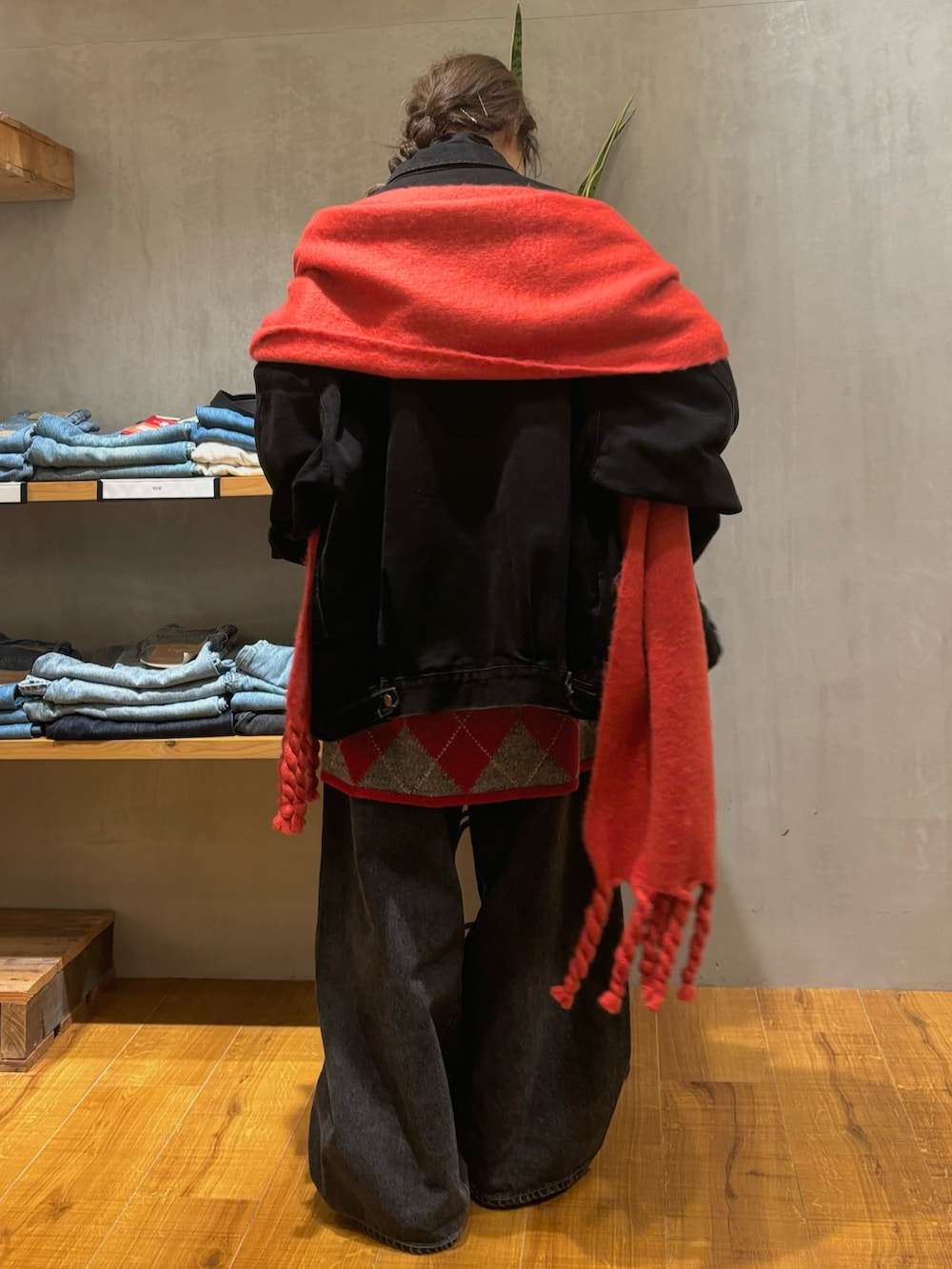 ブラック系のデニムジャケット、レッド系のニット/セーター、ブラック系のデニムパンツを着用したレディースの秋コーディネートの3枚目の写真