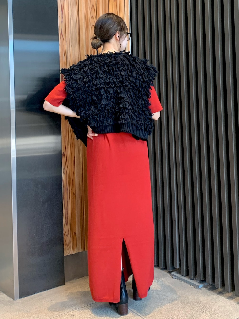 レッド系のワンピース、ブラック系のベスト、ブラック系のブーツを着用したレディースの秋コーディネートの4枚目の写真