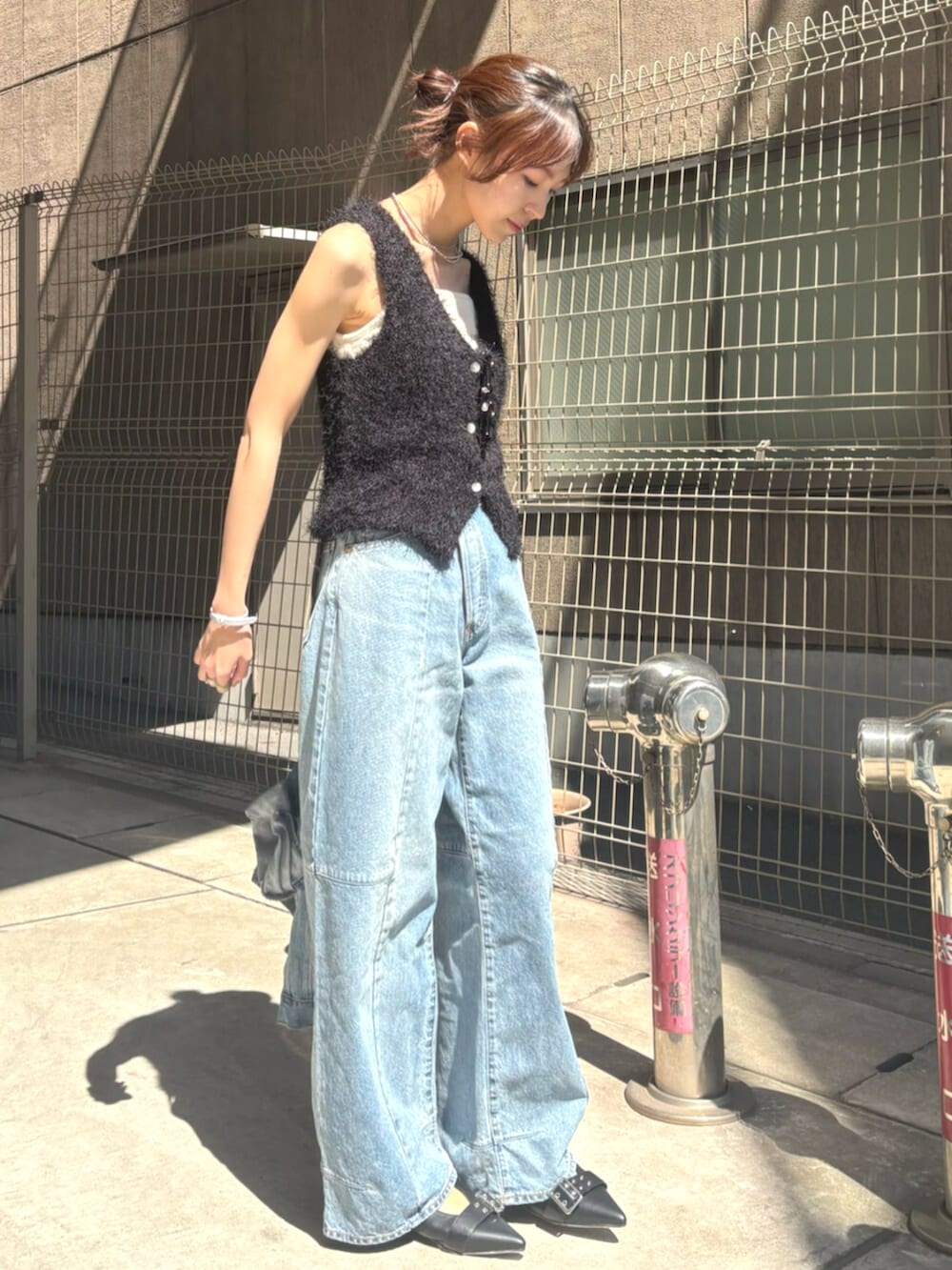 ブラック系のパンプス、ブラック系のベスト、ブルー系のデニムジャケットを着用したレディースの春コーディネートの2枚目の写真