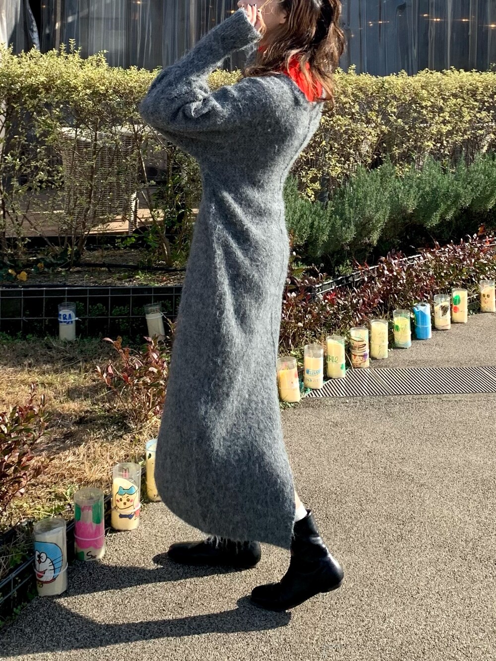 ブラック系のムートンコート、グレー系のワンピース、レッド系のニット/セーターを着用したレディースの冬コーディネートの3枚目の写真