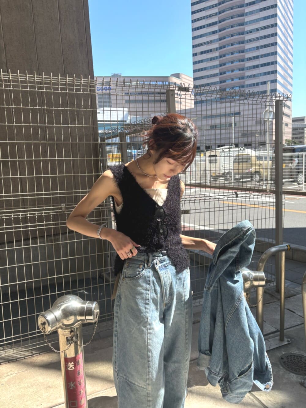 ブラック系のパンプス、ブラック系のベスト、ブルー系のデニムジャケットを着用したレディースの春コーディネートの4枚目の写真