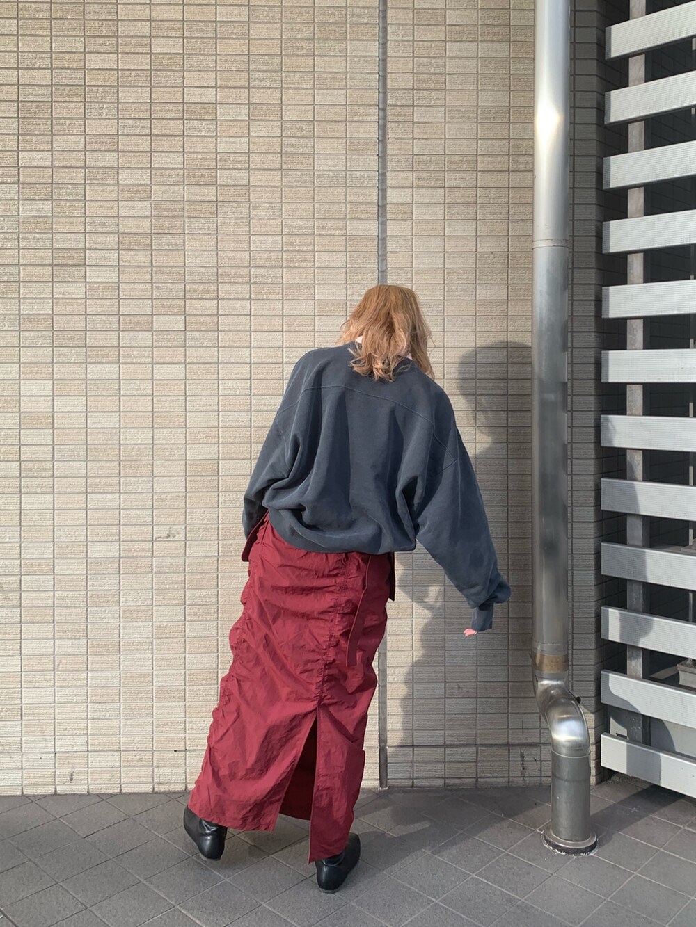 レッド系のスカート、グレー系のスウェット、ブラック系のブーツを着用したレディースの冬コーディネートの3枚目の写真