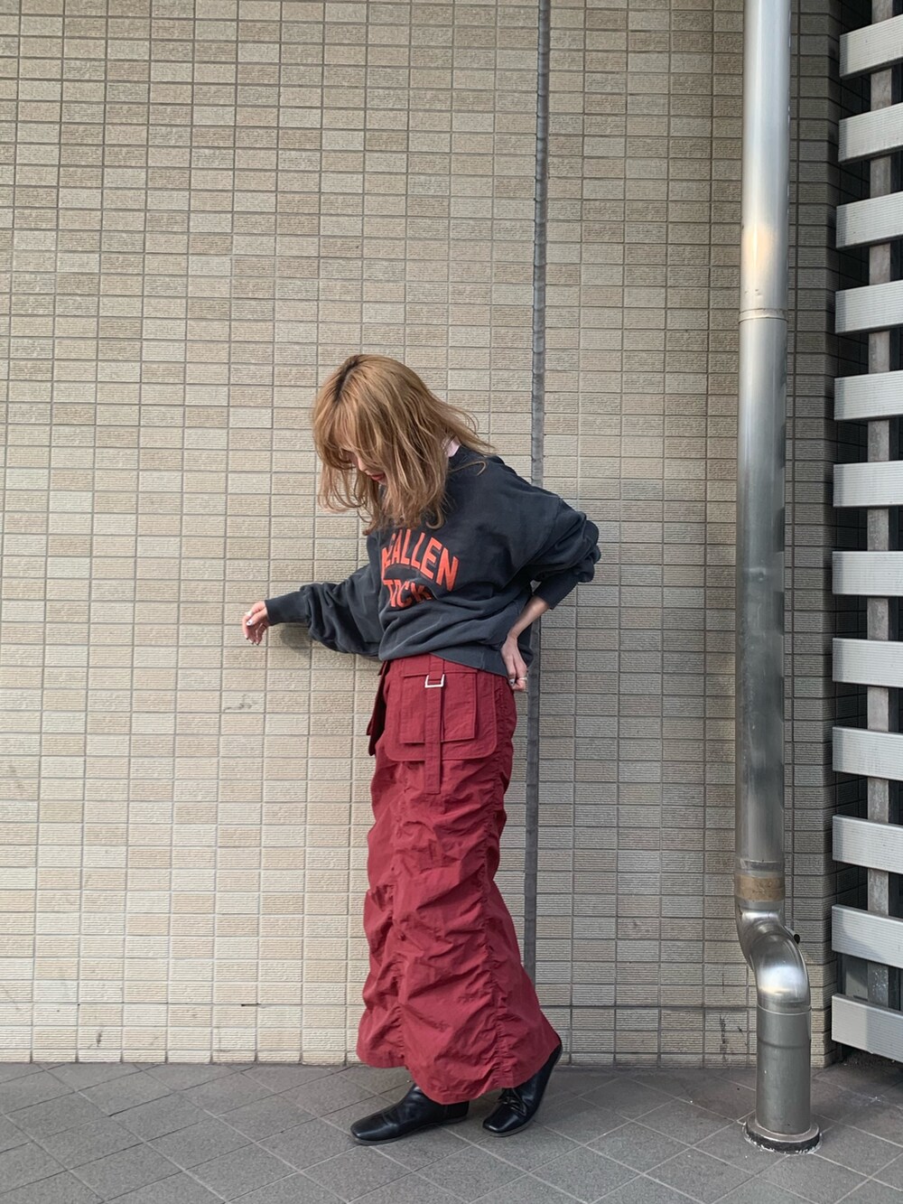 レッド系のスカート、グレー系のスウェット、ブラック系のブーツを着用したレディースの冬コーディネートの2枚目の写真