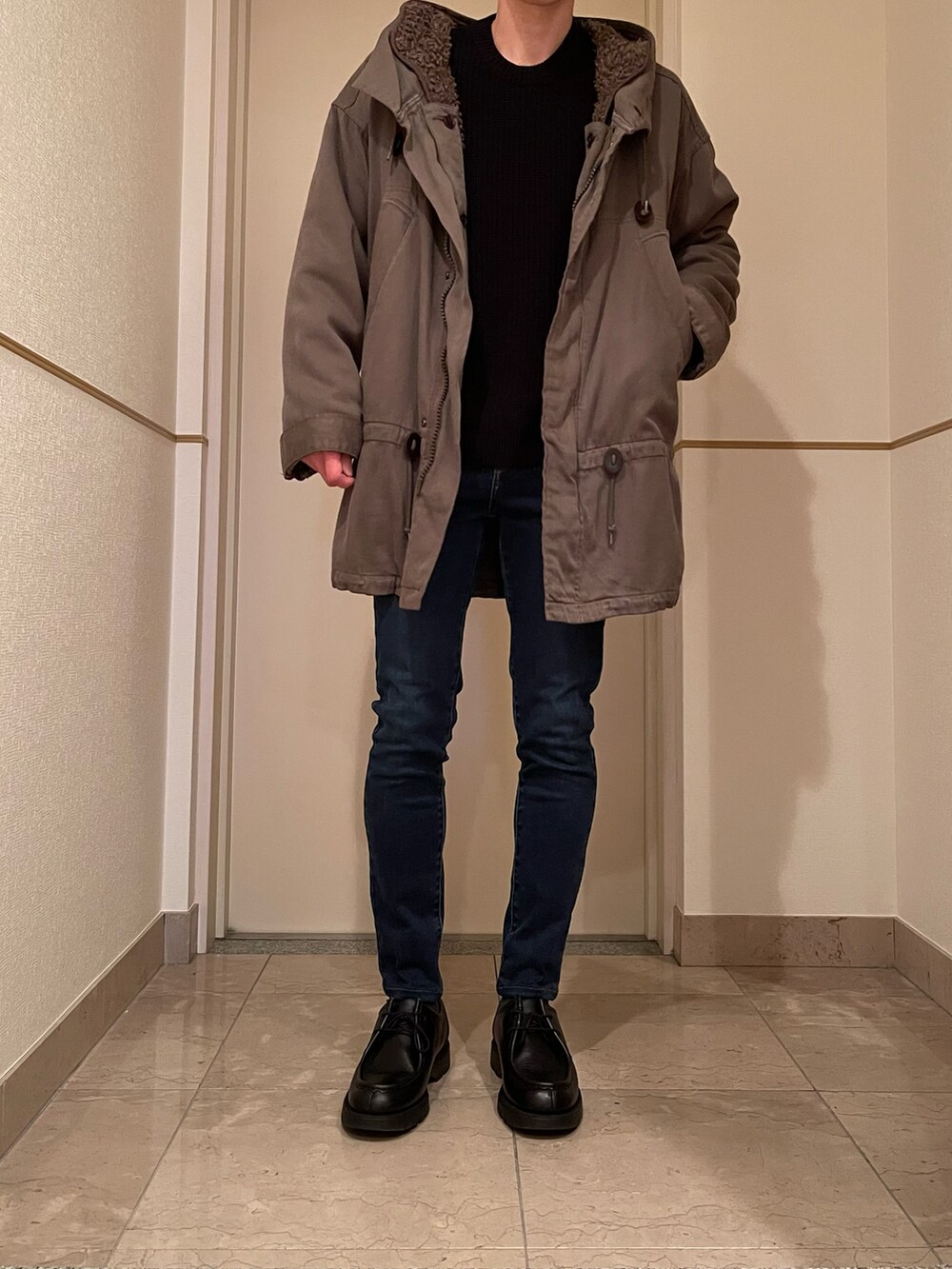 ブラック系のニット/セーター、ブルー系のデニムパンツ、ブラック系のブーツを着用したメンズの冬コーディネートの2枚目の写真