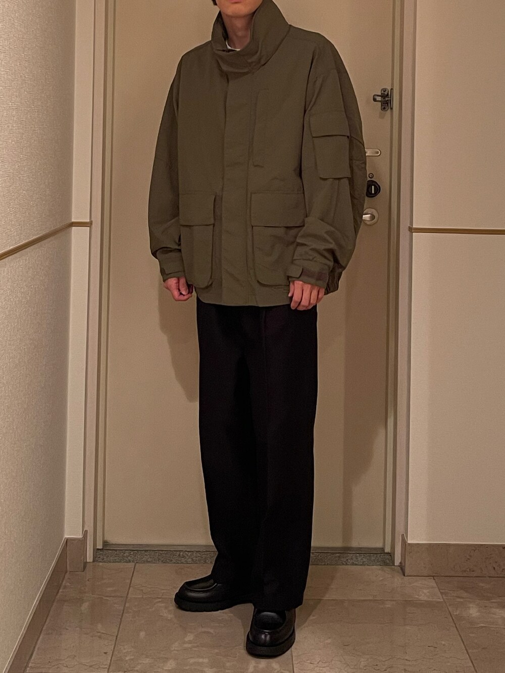 グリーン系のジャケット/アウター、ブラック系のパンツ、ブラック系のシューズを着用したメンズの春コーディネートの2枚目の写真