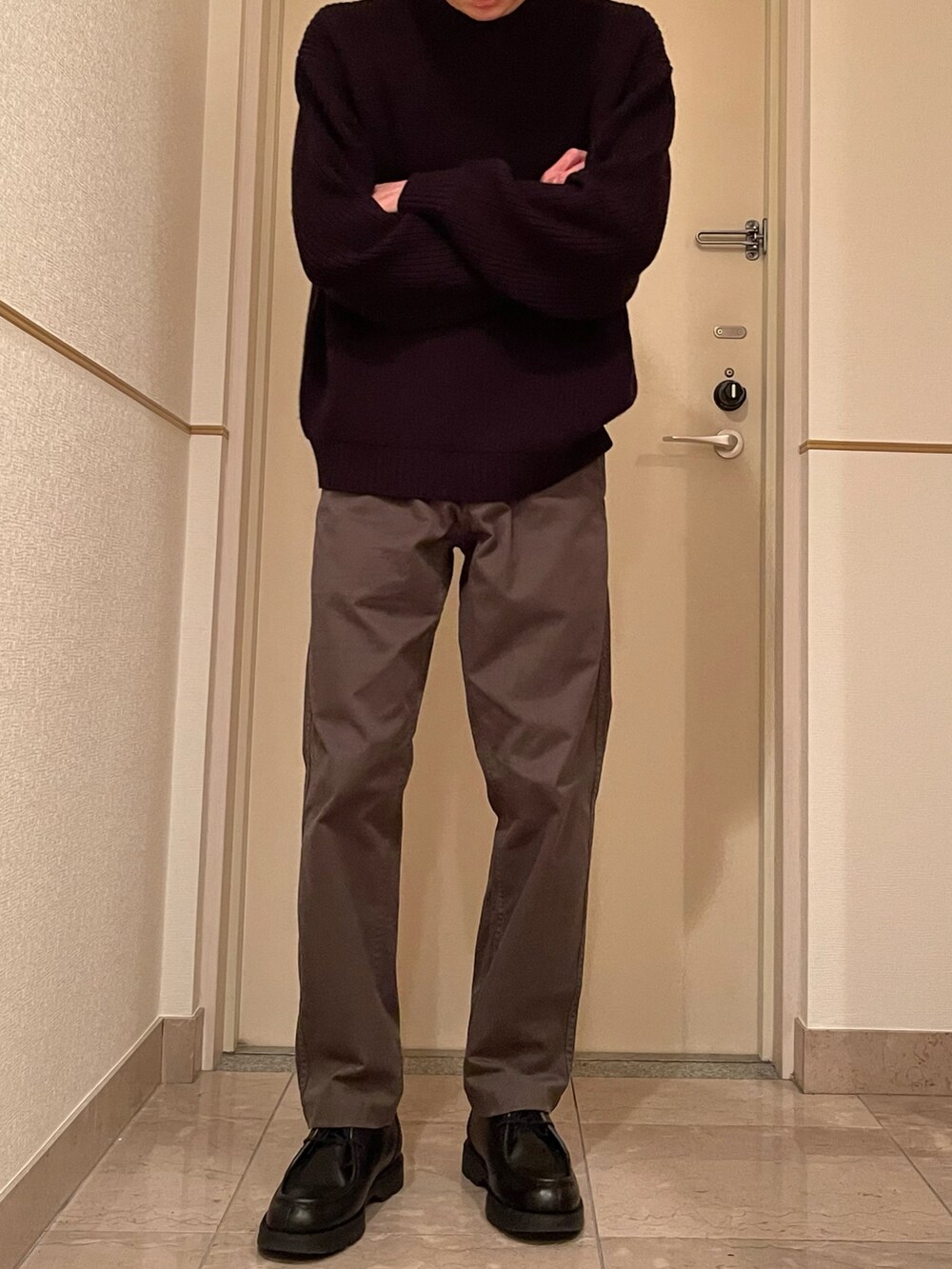 グリーン系のチノパンツ、ブラック系のニット/セーター、ブラック系のブーツを着用したメンズの春コーディネートの2枚目の写真