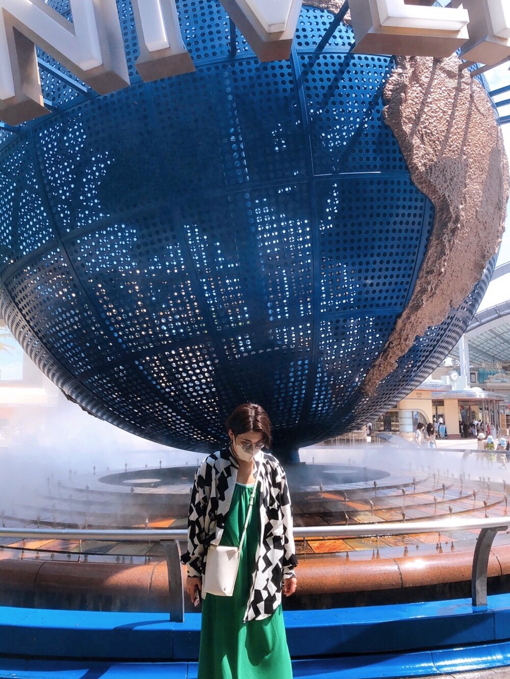 ブラック系のサンダル、グリーン系のワンピース、ホワイト系のショルダーバッグを着用したレディースの夏コーディネートの2枚目の写真