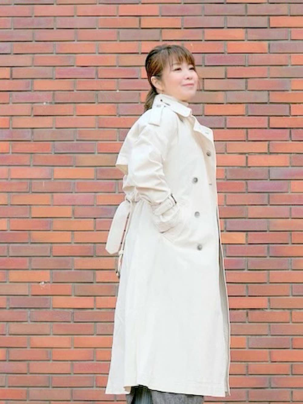 ブラウン系のショルダーバッグ、ホワイト系のトレンチコートを着用したレディースの春コーディネートの2枚目の写真