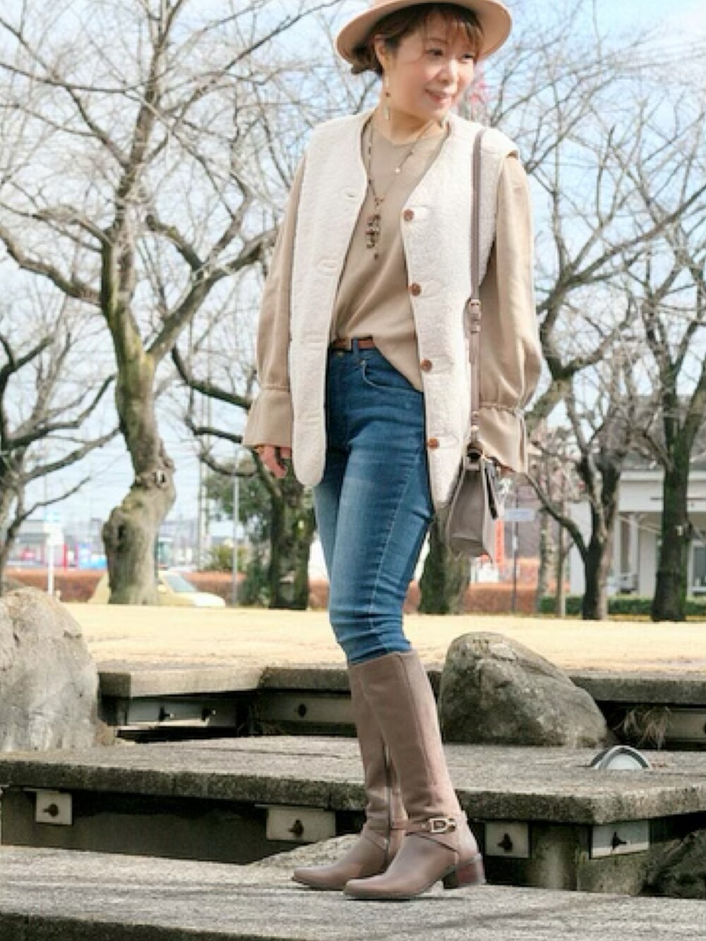 ブラウン系のブーツ、ブルー系のデニムパンツを着用したレディースの春コーディネートの2枚目の写真
