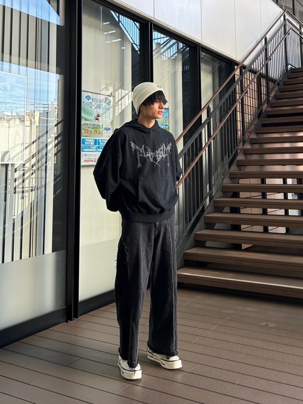 ブラック系のパーカー、ブラック系のデニムパンツ、ホワイト系のスニーカーを着用したメンズの冬コーディネートの2枚目の写真