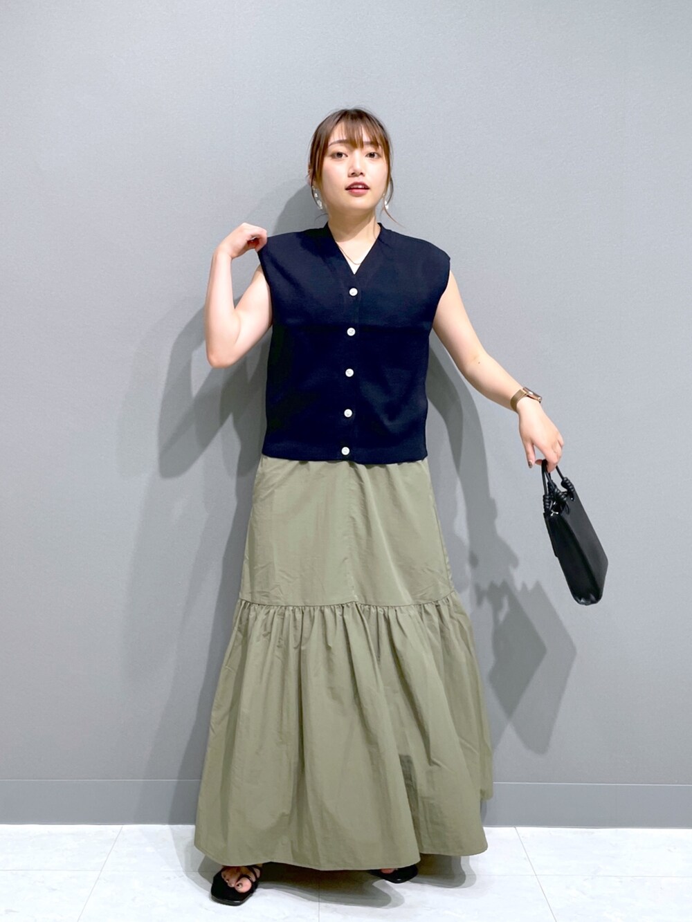 グリーン系のワンピース、ブルー系のニット/セーター、ブラック系のショルダーバッグを着用したレディースの夏コーディネートの2枚目の写真