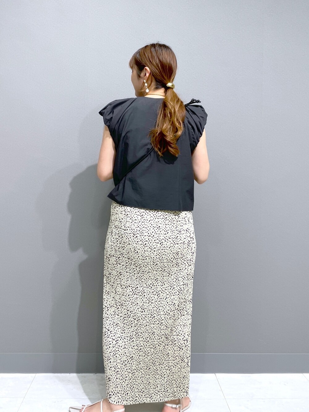 ベージュ系のスカート、ブラック系のシャツ/ブラウス、ブラック系のショルダーバッグを着用したレディースの夏コーディネートの2枚目の写真