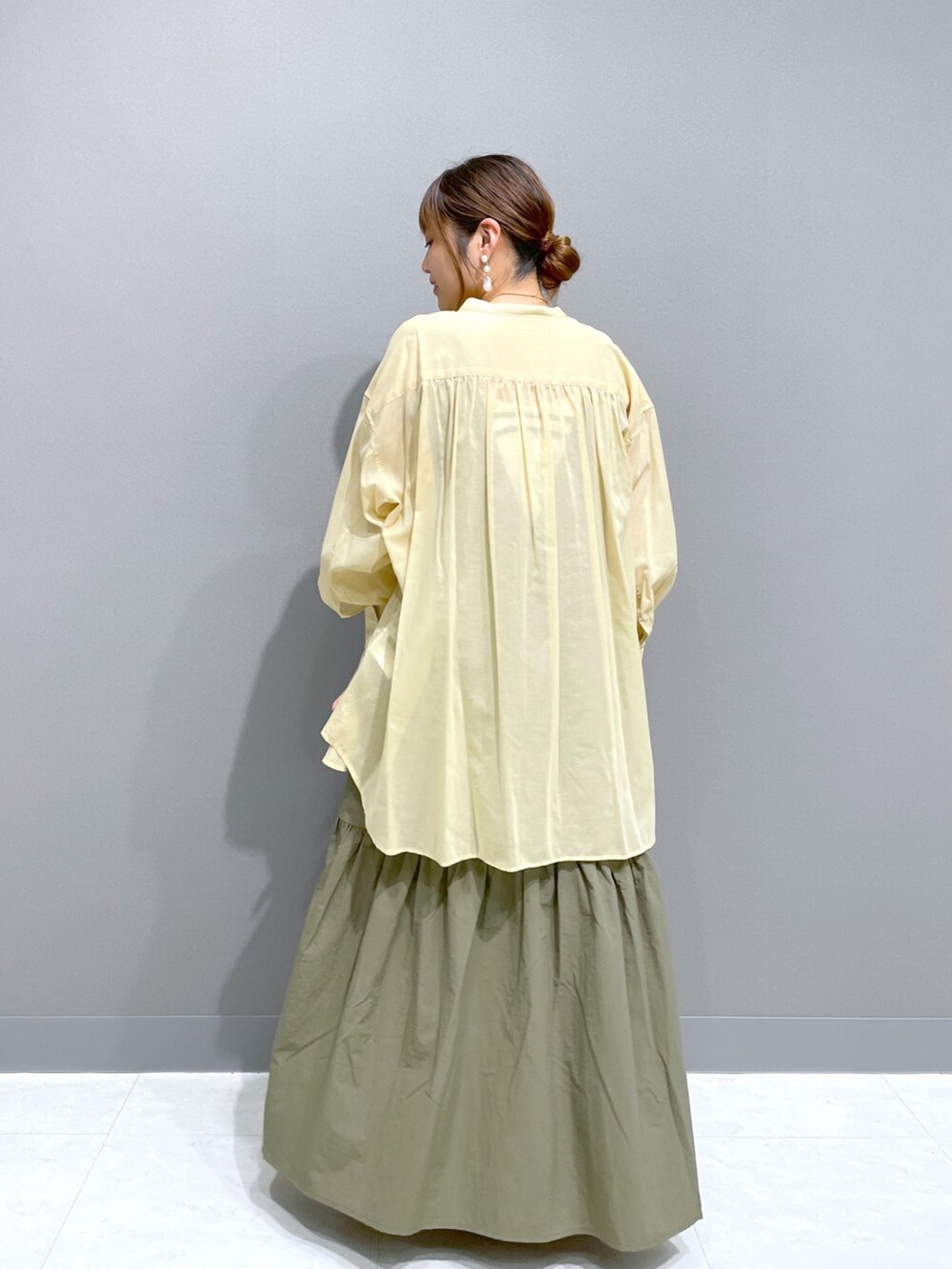 グリーン系のワンピース、イエロー系のシャツ/ブラウス、ホワイト系のタンクトップを着用したレディースの夏コーディネートの2枚目の写真