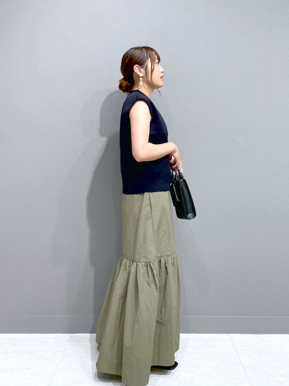 グリーン系のワンピース、ブルー系のニット/セーター、ブラック系のショルダーバッグを着用したレディースの夏コーディネートの3枚目の写真