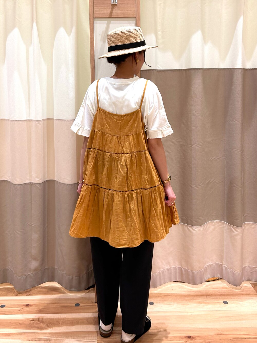 イエロー系のチュニック、ブラック系のその他パンツ、ブラック系のサンダルを着用したレディースの春コーディネートの2枚目の写真