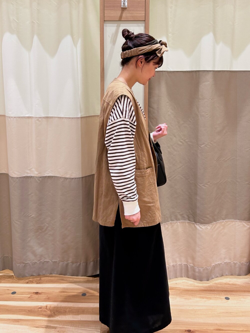 ホワイト系のTシャツ/カットソー、ブラック系のハンドバッグ、ベージュ系のベストを着用したレディースの春コーディネートの2枚目の写真