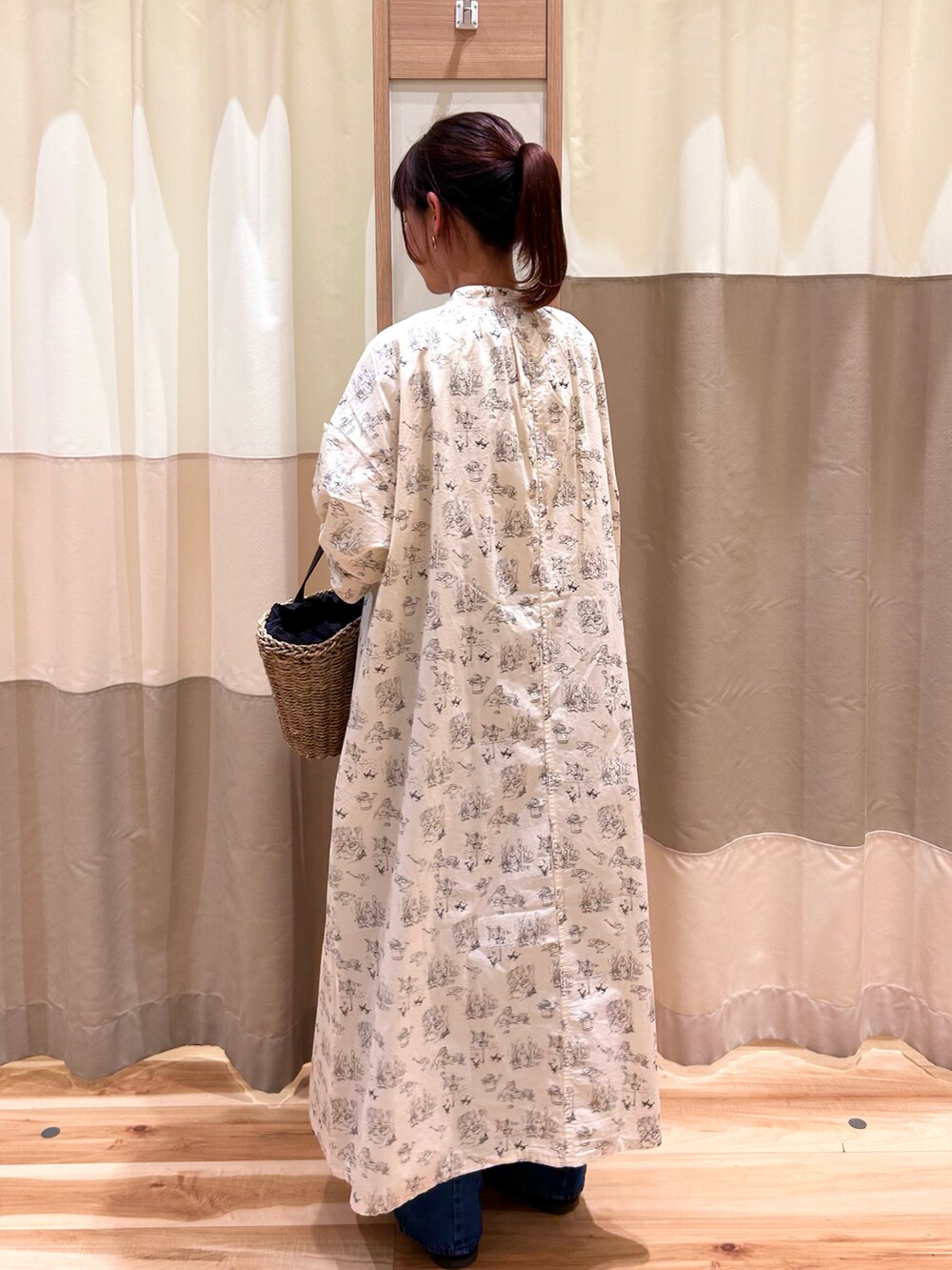 ブラック系のハンドバッグ、ブルー系のデニムパンツ、ホワイト系のワンピースを着用したレディースの春コーディネートの3枚目の写真