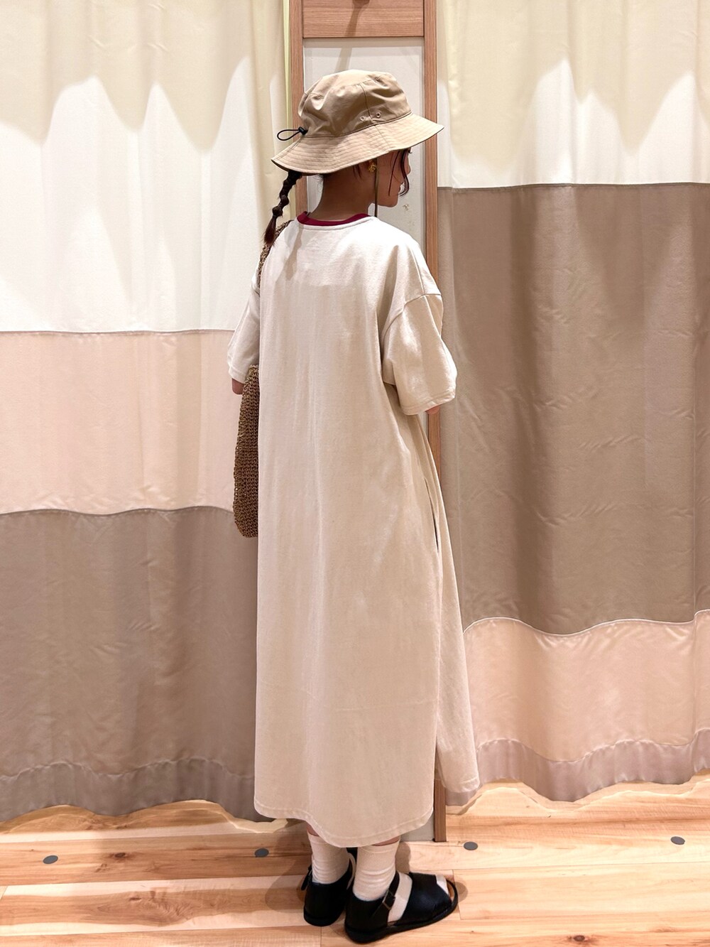 ブラック系のサンダル、ベージュ系のワンピース、ベージュ系のハンドバッグを着用したレディースの春コーディネートの2枚目の写真