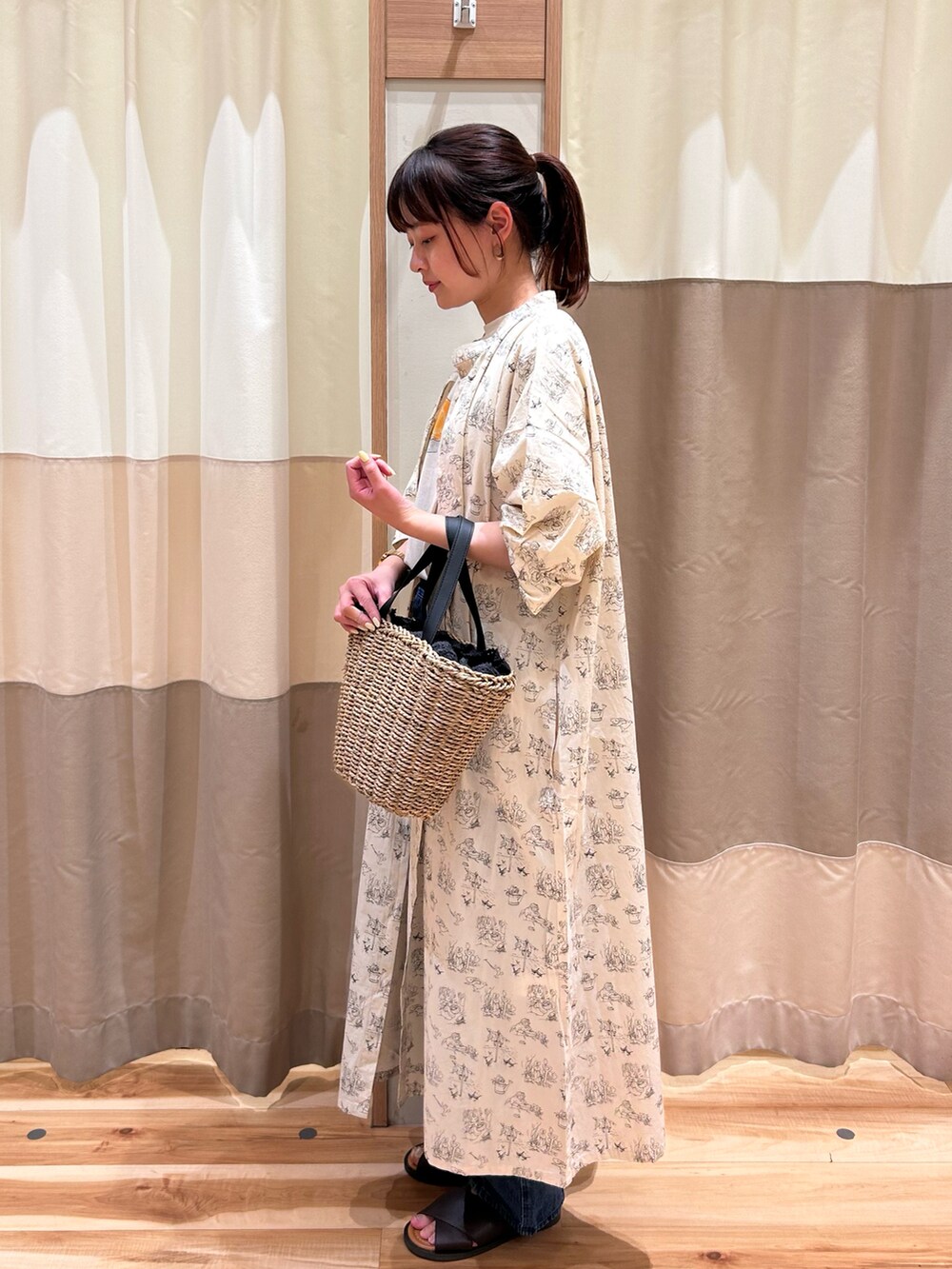 ブラック系のハンドバッグ、ブルー系のデニムパンツ、ホワイト系のワンピースを着用したレディースの春コーディネートの2枚目の写真