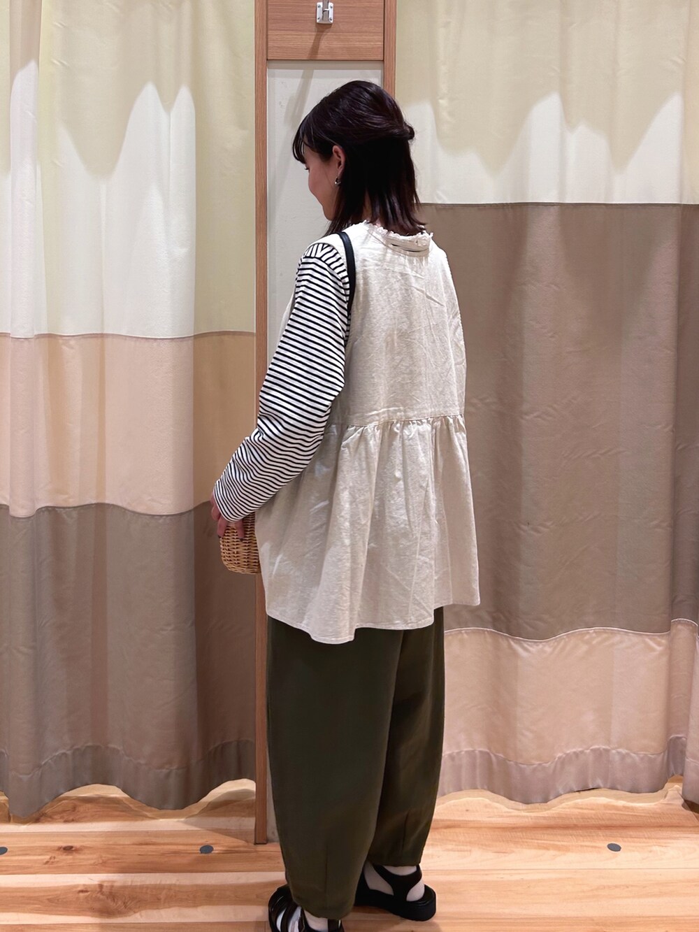 ホワイト系のベスト、ホワイト系のTシャツ/カットソー、ブラック系のサンダルを着用したレディースの春コーディネートの2枚目の写真