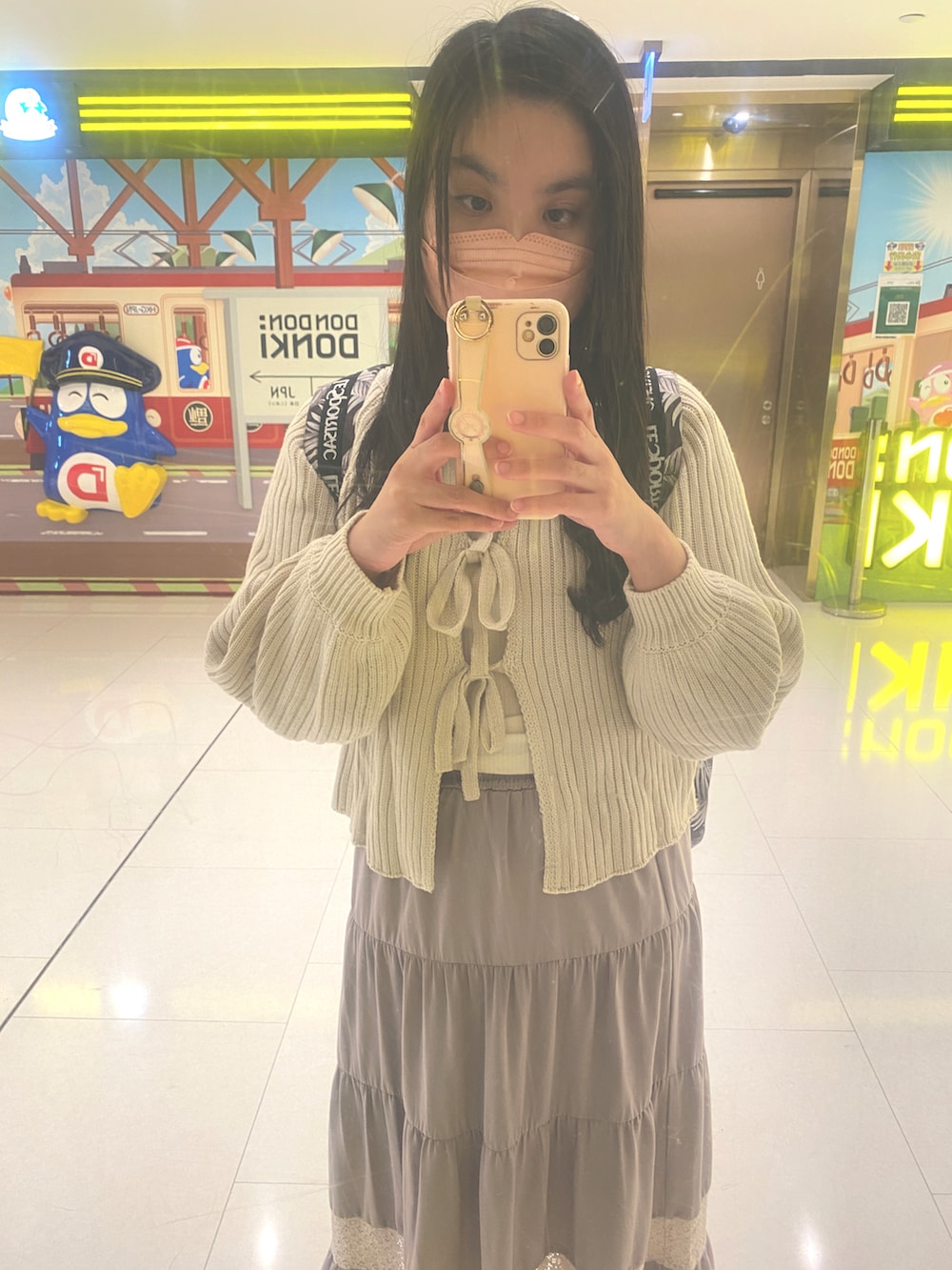 ピンク系のスカート、ベージュ系のニット/セーター、ホワイト系のトップスを着用したレディースの秋コーディネートの2枚目の写真