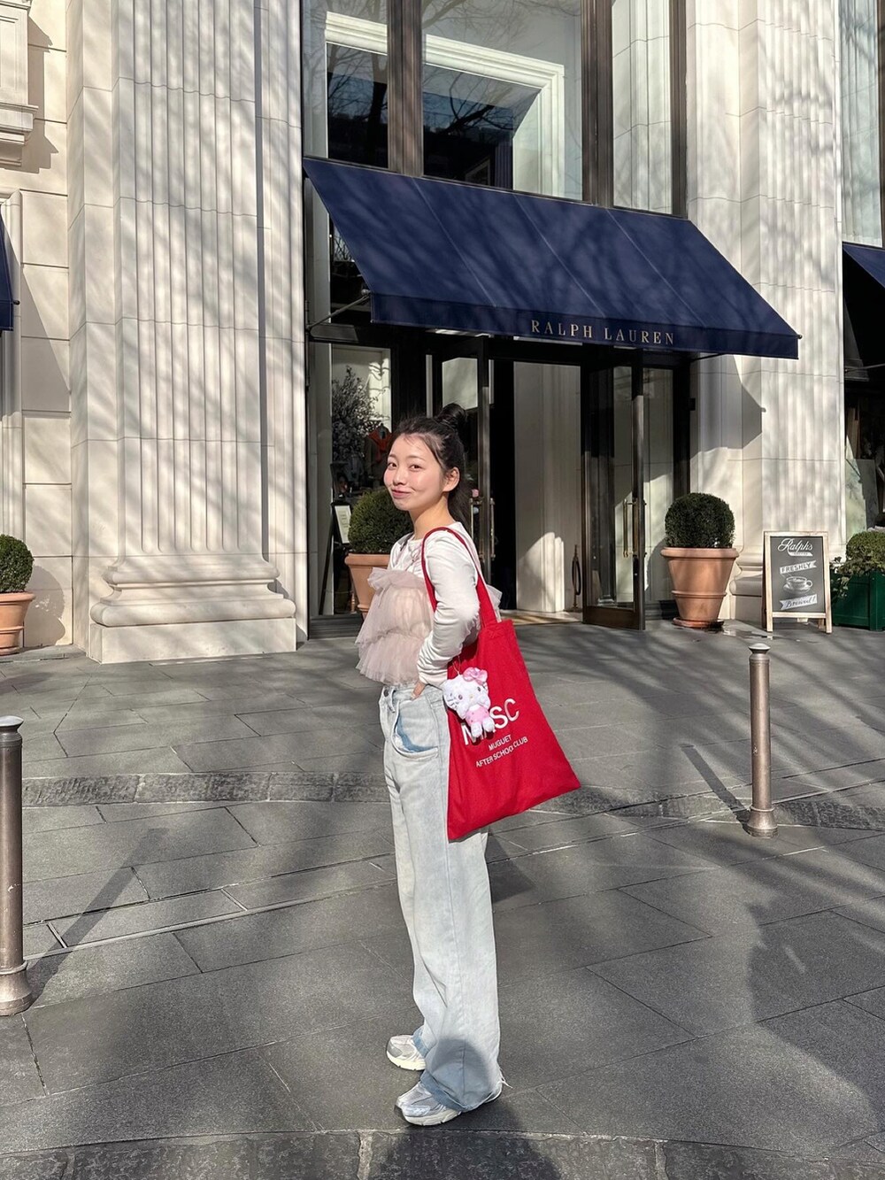 レッド系のトートバッグ、パープル系のアンサンブル、グレー系のスニーカーを着用したレディースの春コーディネートの3枚目の写真