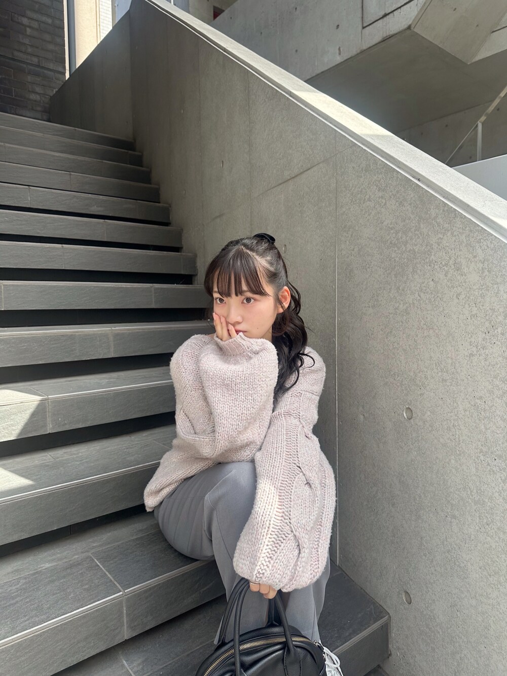 パープル系のニット/セーター、グレー系のスラックス、グレー系のスニーカーを着用したレディースの秋コーディネートの5枚目の写真