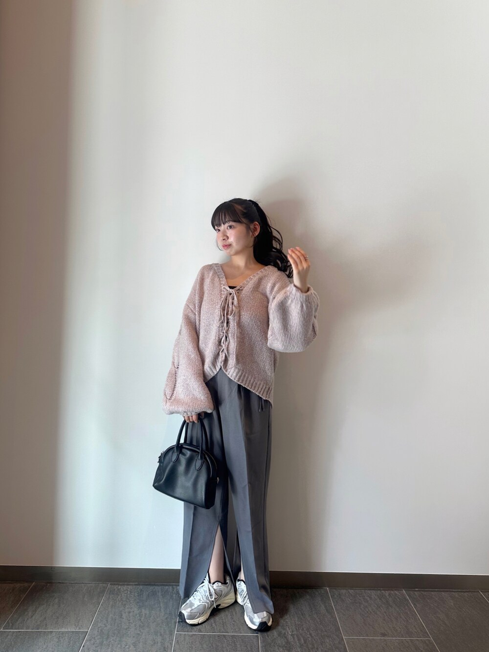 パープル系のニット/セーター、グレー系のスラックス、グレー系のスニーカーを着用したレディースの秋コーディネートの3枚目の写真