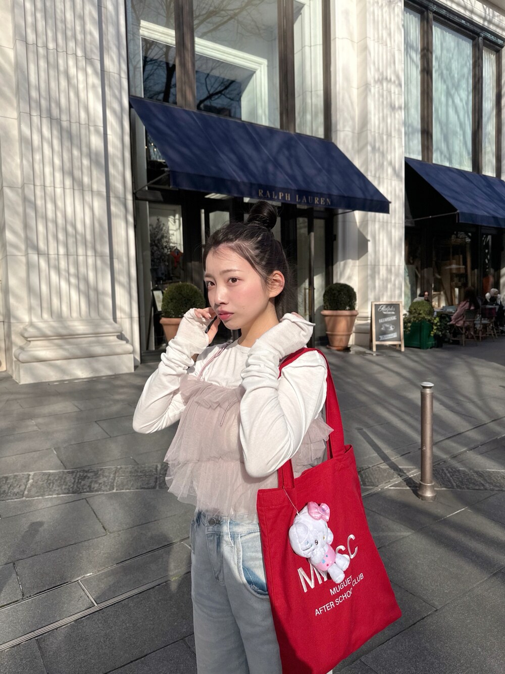 レッド系のトートバッグ、パープル系のアンサンブル、グレー系のスニーカーを着用したレディースの春コーディネートの2枚目の写真