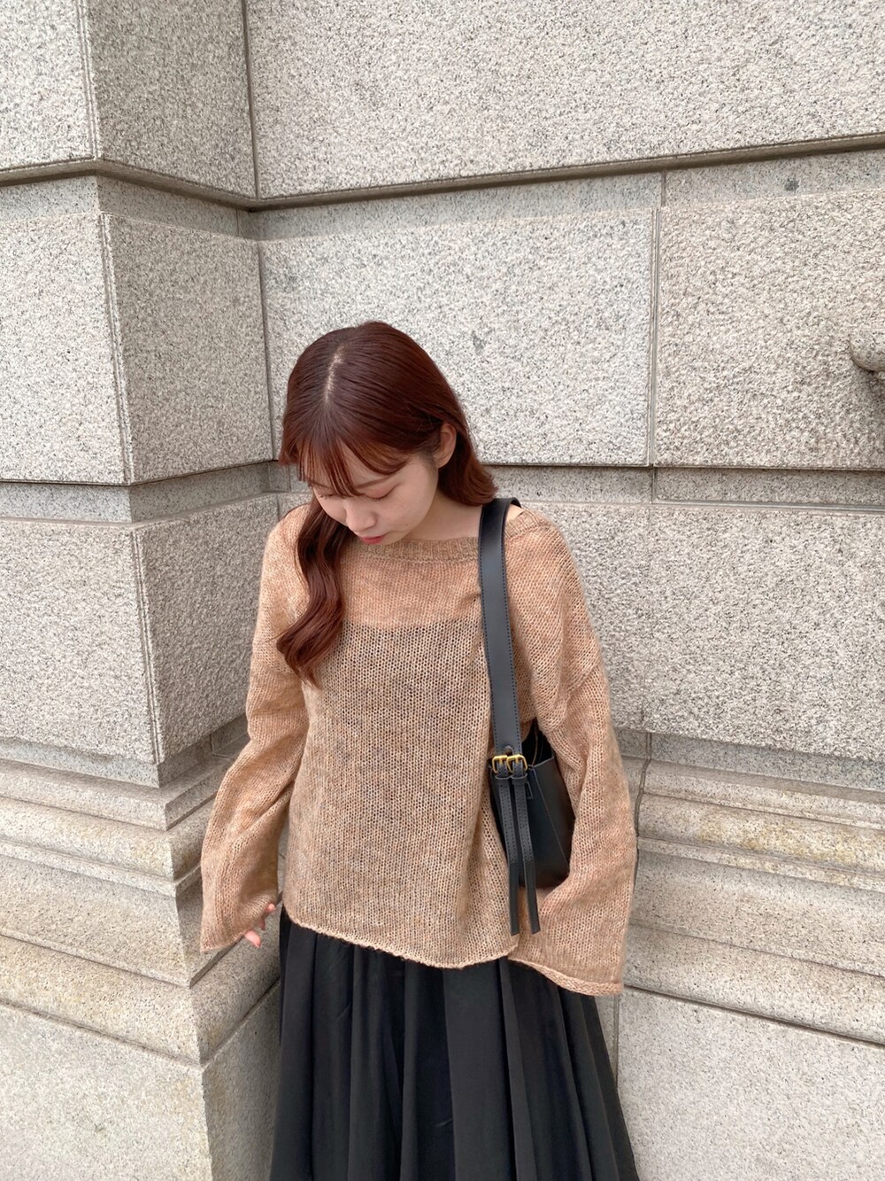 ブラウン系のニット/セーター、ブラック系のスカート、ブラック系のブーツを着用したレディースの秋コーディネートの4枚目の写真