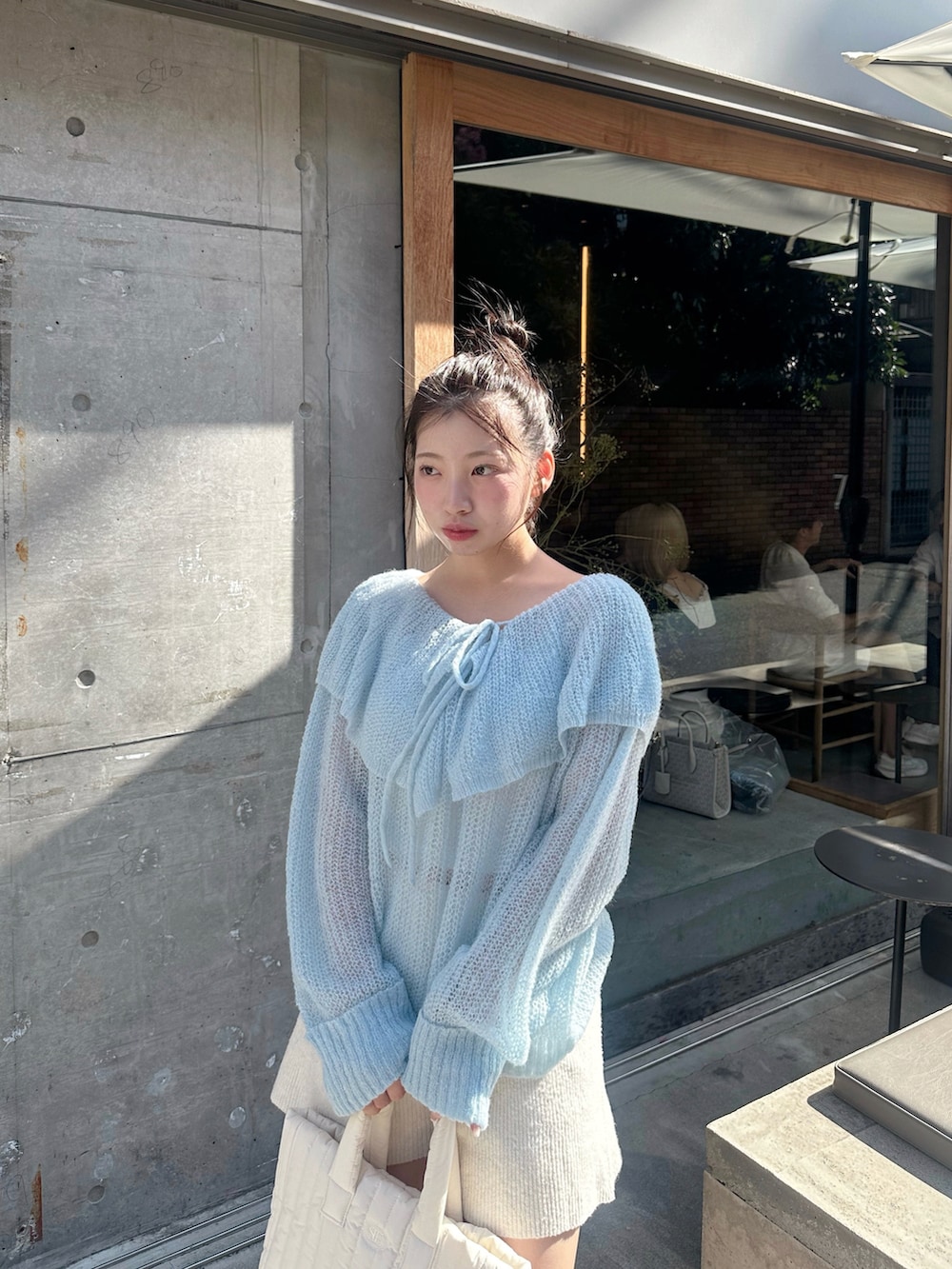 ブルー系のニット/セーター、ホワイト系のパンツ、ホワイト系のバッグを着用したレディースの秋コーディネートの2枚目の写真