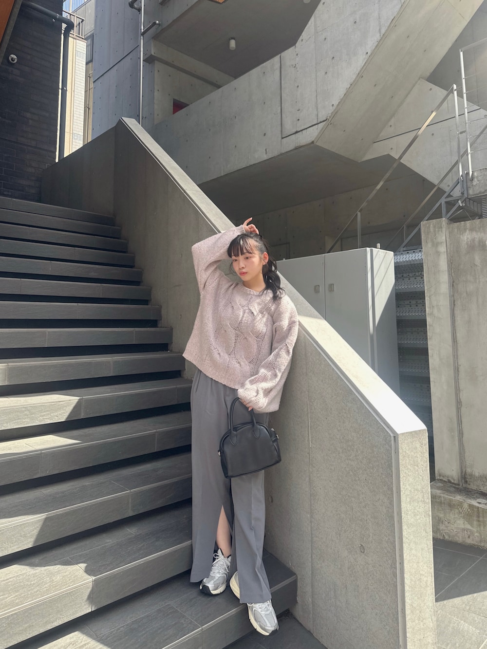 パープル系のニット/セーター、グレー系のスラックス、グレー系のスニーカーを着用したレディースの秋コーディネートの4枚目の写真