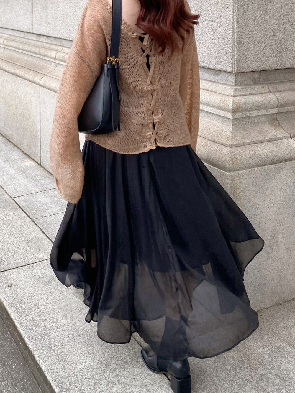 ブラウン系のニット/セーター、ブラック系のスカート、ブラック系のブーツを着用したレディースの秋コーディネートの3枚目の写真