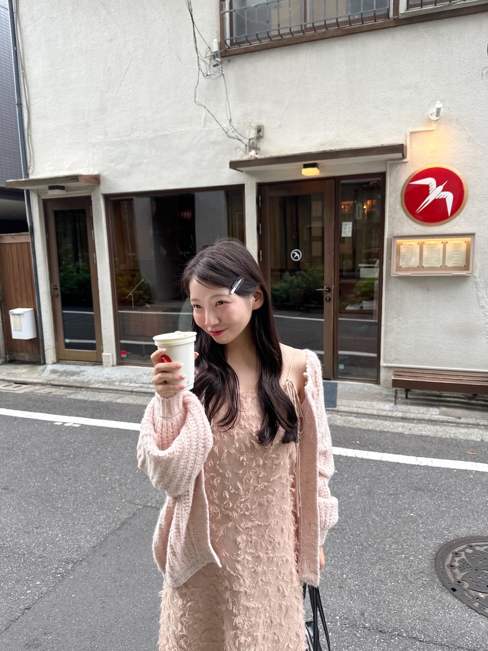 ピンク系のワンピース、ピンク系のカーディガン/ボレロ、ブラック系のショルダーバッグを着用したレディースの秋コーディネートの2枚目の写真