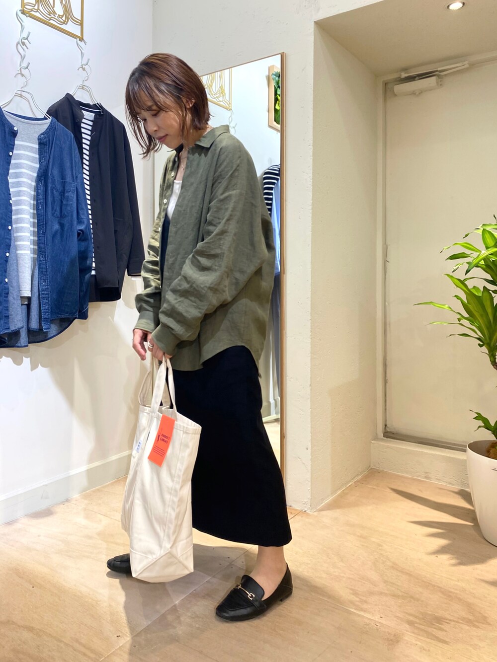 グリーン系のシャツ/ブラウス、ホワイト系のトートバッグを着用したレディースの秋コーディネートの2枚目の写真