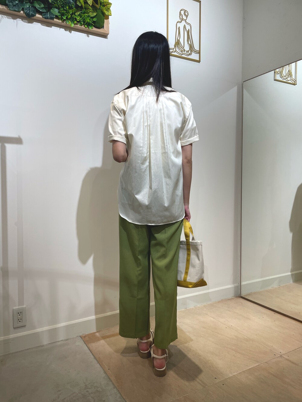 イエロー系のシャツ/ブラウス、イエロー系のトートバッグ、グリーン系のスラックスを着用したレディースの夏コーディネートの2枚目の写真