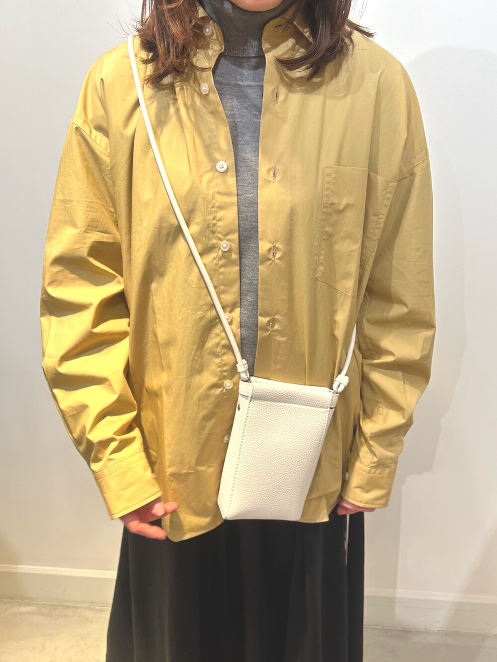 ベージュ系のショルダーバッグ、ブラック系のスカート、ベージュ系のシャツ/ブラウスを着用したレディースの冬コーディネートの4枚目の写真