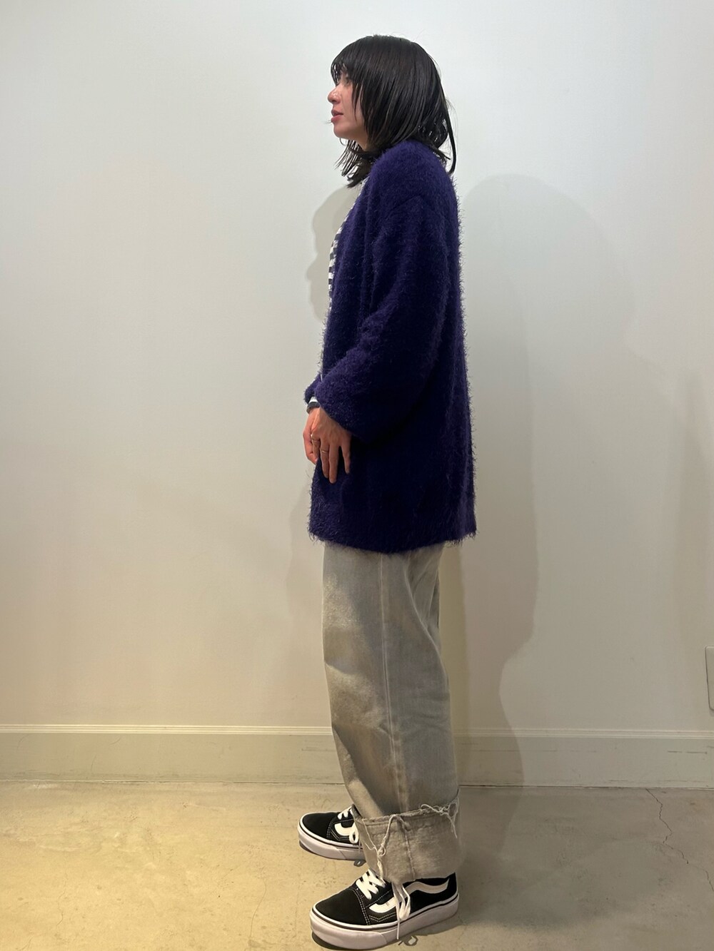 ブラック系のスニーカー、グレー系のデニムパンツ、パープル系のカーディガン/ボレロを着用したレディースの秋コーディネートの2枚目の写真