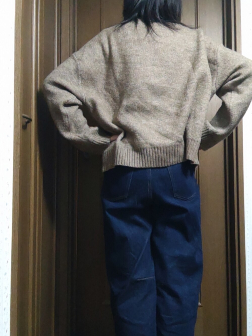 ブルー系のデニムパンツ、ブラック系のショルダーバッグ、ブラウン系のニット/セーターを着用したレディースの冬コーディネートの3枚目の写真