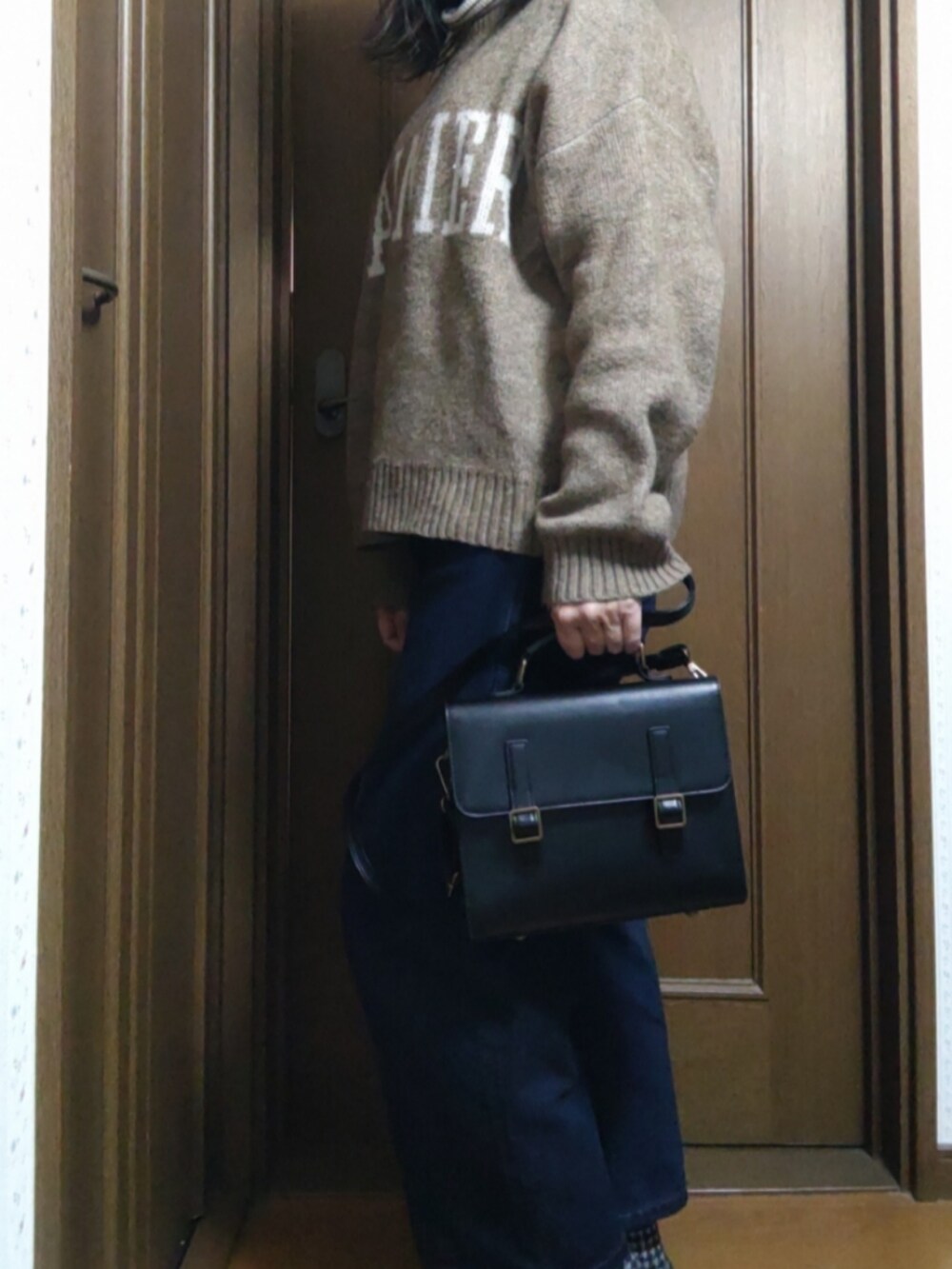 ブルー系のデニムパンツ、ブラック系のショルダーバッグ、ブラウン系のニット/セーターを着用したレディースの冬コーディネートの2枚目の写真