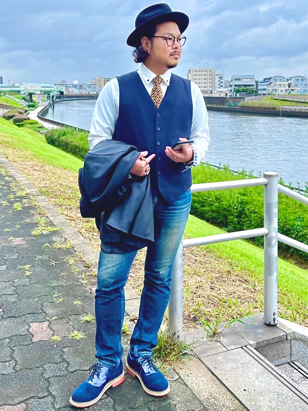 ブルー系のデニムパンツ、ブルー系のドレスシューズ、ブルー系のベストを着用したメンズの秋コーディネートの3枚目の写真