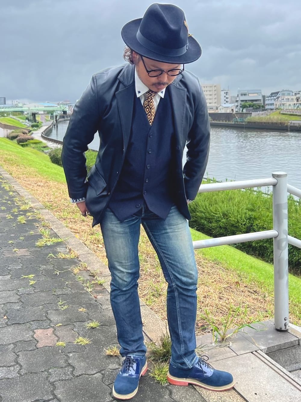 ブルー系のデニムパンツ、ブルー系のドレスシューズ、ブルー系のベストを着用したメンズの秋コーディネートの2枚目の写真
