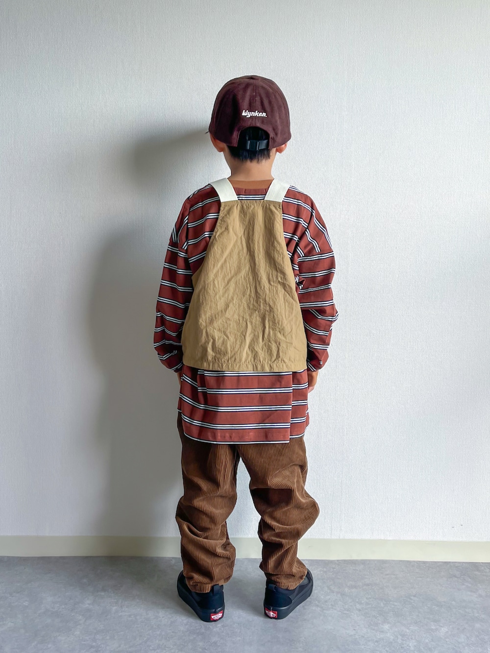 ベージュ系のベスト、ブラウン系のTシャツ/カットソー、ブラック系のスニーカーを着用したキッズの秋コーディネートの2枚目の写真