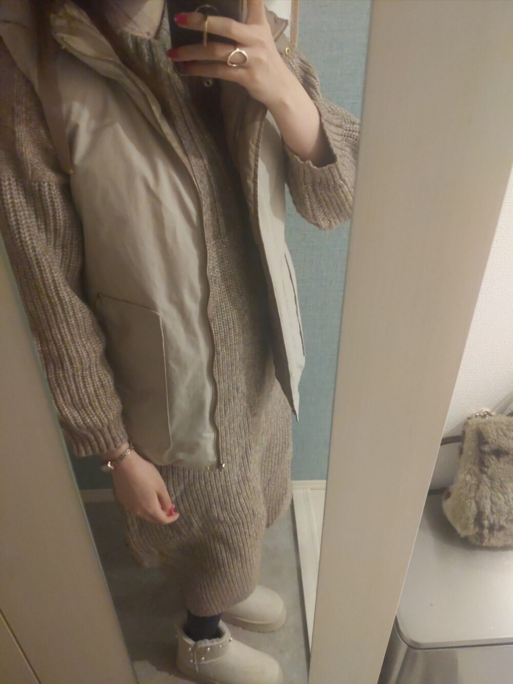 ブラウン系のショルダーバッグ、ブラウン系のワンピース、ベージュ系のダウンベストを着用したレディースの秋コーディネートの2枚目の写真