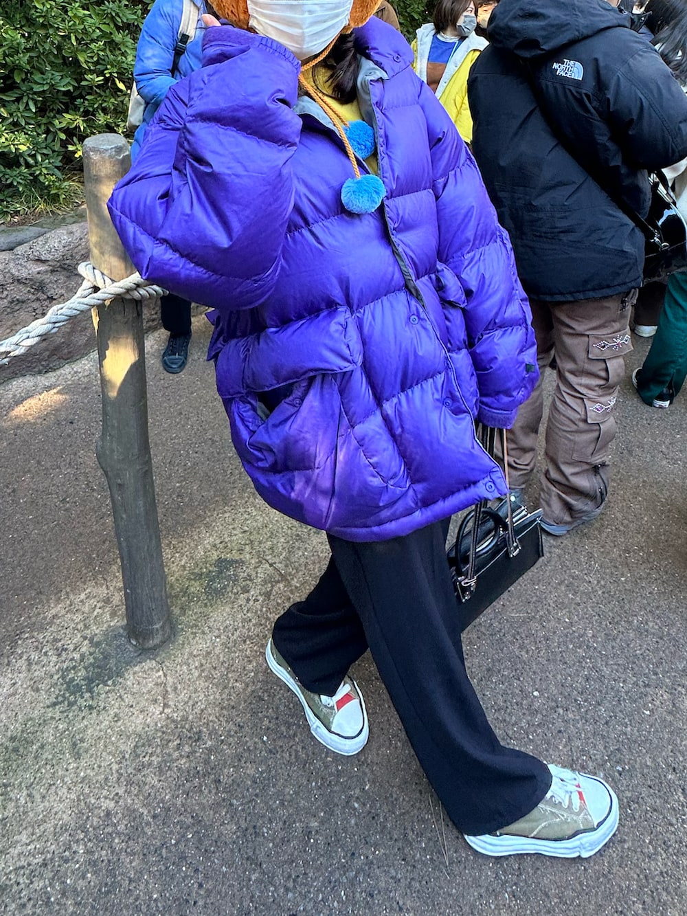 ブラック系のスラックス、その他のスニーカー、パープル系のダウンジャケット/コートを着用したレディースの冬コーディネートの2枚目の写真