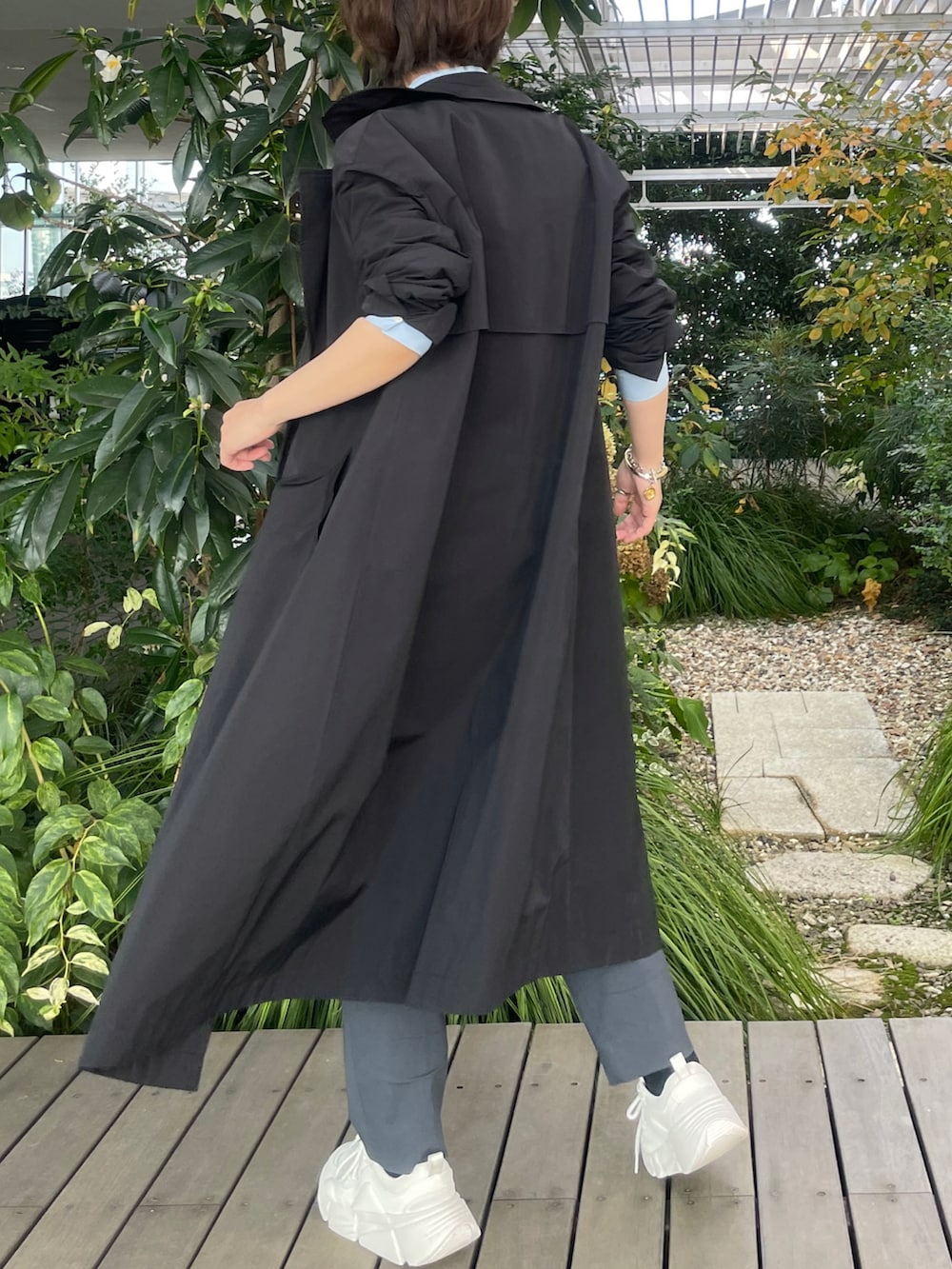 ブラック系のトレンチコート、グレー系のその他パンツ、ホワイト系のスニーカーを着用したレディースの秋コーディネートの2枚目の写真