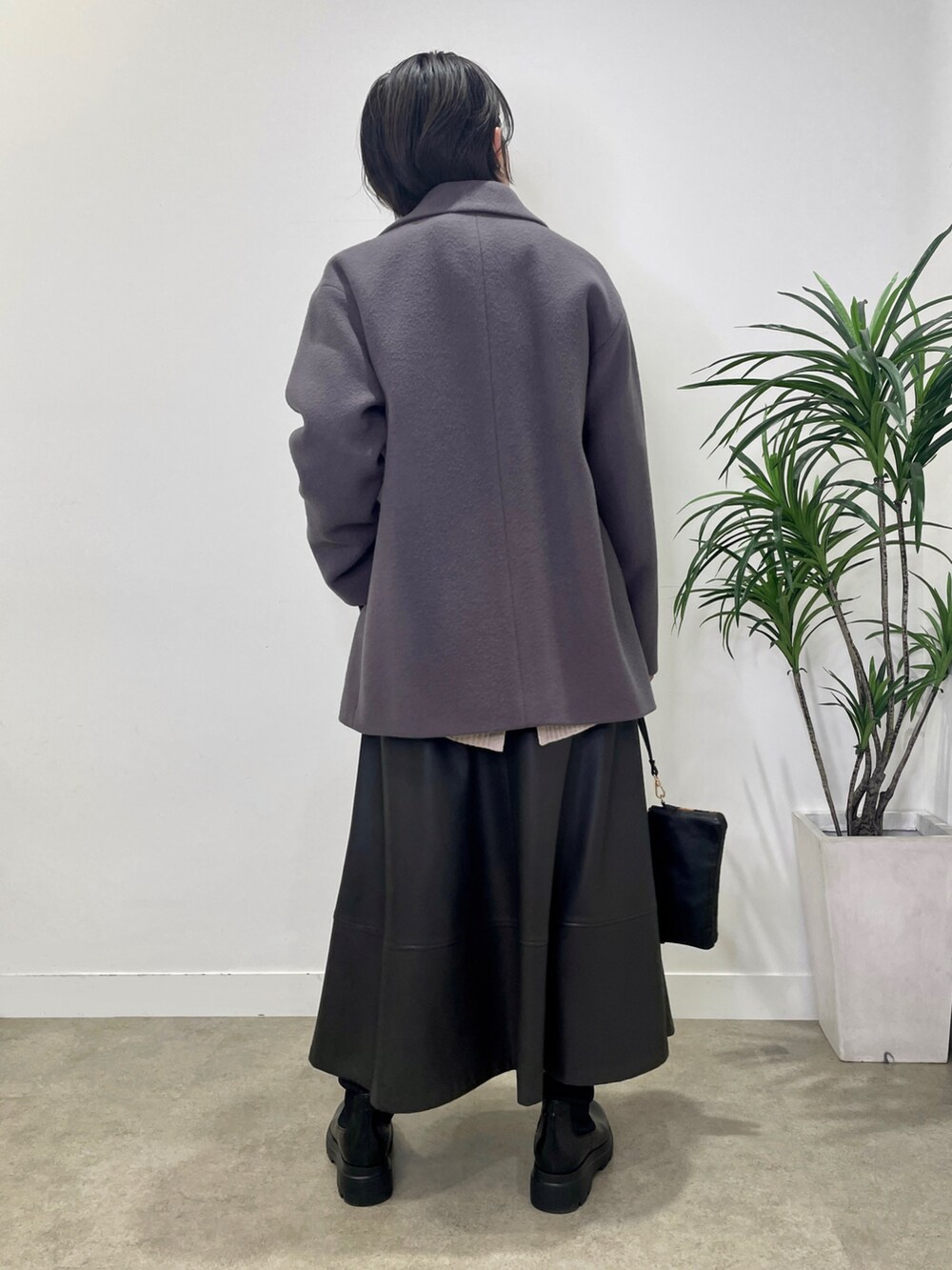 パープル系のニット/セーター、グレー系のステンカラーコート、グレー系のスカートを着用したレディースの冬コーディネートの3枚目の写真