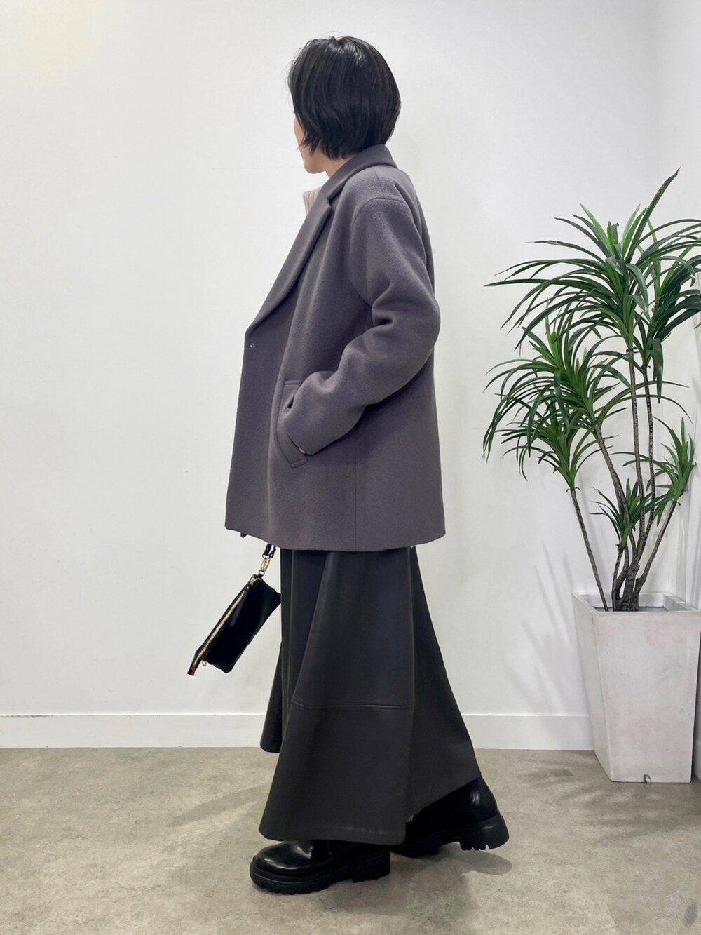 パープル系のニット/セーター、グレー系のステンカラーコート、グレー系のスカートを着用したレディースの冬コーディネートの2枚目の写真